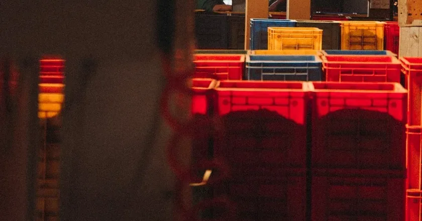 Intralogistyka — stacked warehouse crates under a red indicator light, photo by Klara Kulikova on Unsplash